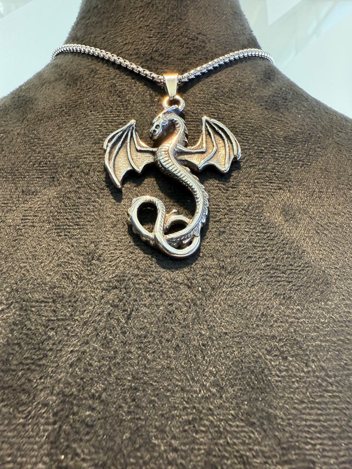 Silver dragon pendant on a mannequin neck with a clear background