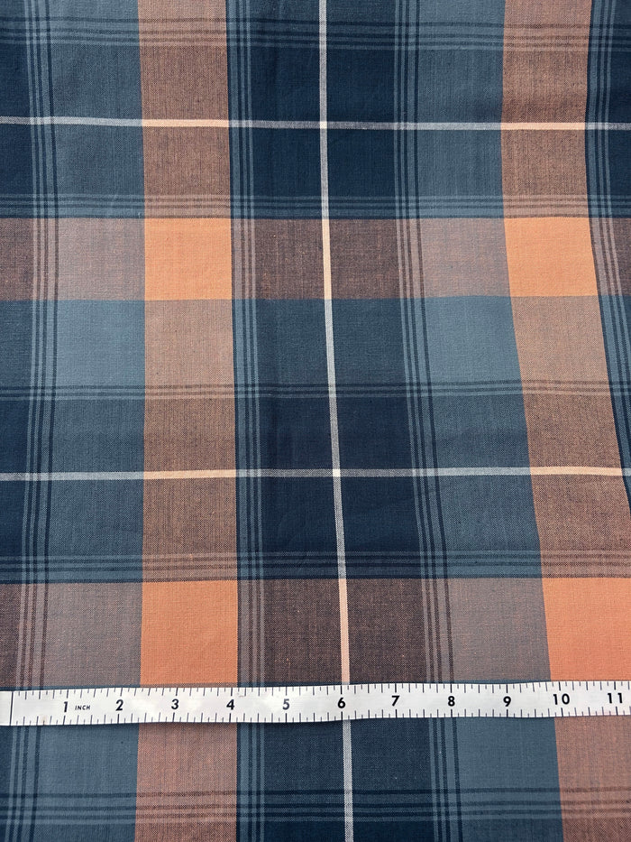 Plaid fabric with blue and oranges with a ruler at the bottom for scale