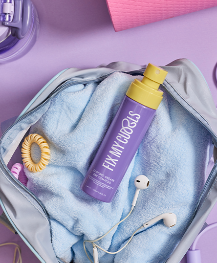 Goodbye Grease Dry Shampoo on a blue towel inside an open suitcase