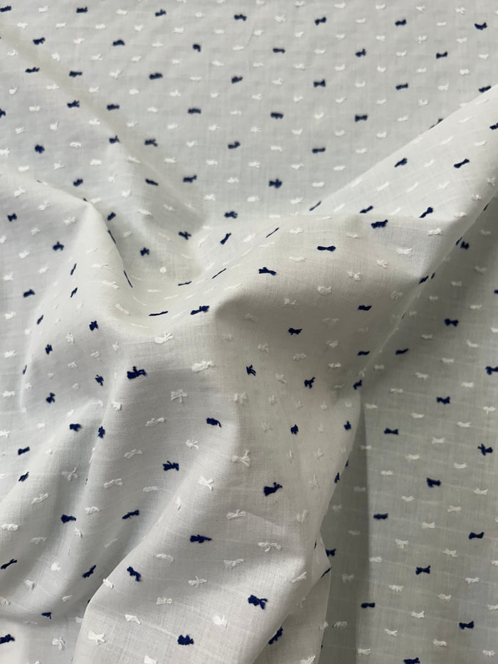Italian cotton fil coupé fabric features a subtle jacquard-woven Swiss Dot pattern in white and navy on a white background.