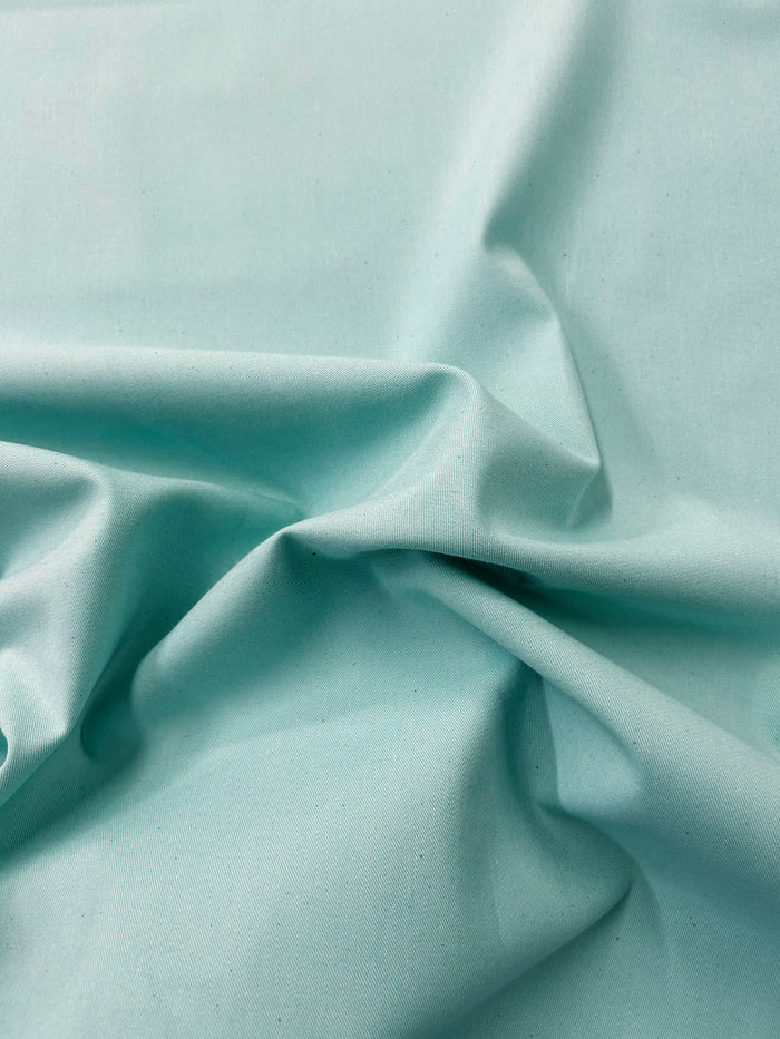 Close-up of Aqua cotton denim fabric in folds.