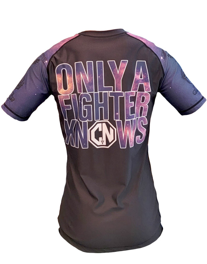 The Retro Grappler Only a Fighter Knows Galaxy Rashguard is a black and purple athletic shirt with galaxy-patterned sleeves, four-way stretch fabric, a fitted design, and bold text “ONLY A FIGHTER KNOWS” with a stylized logo on the back.