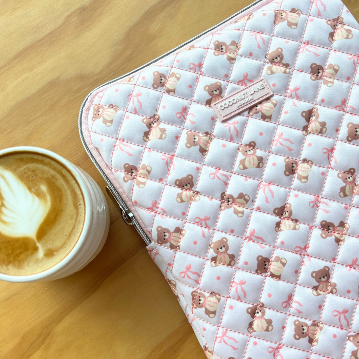 Beige Coconut Lane quilted teddy iPad sleeve next to a latte on a wooden table.