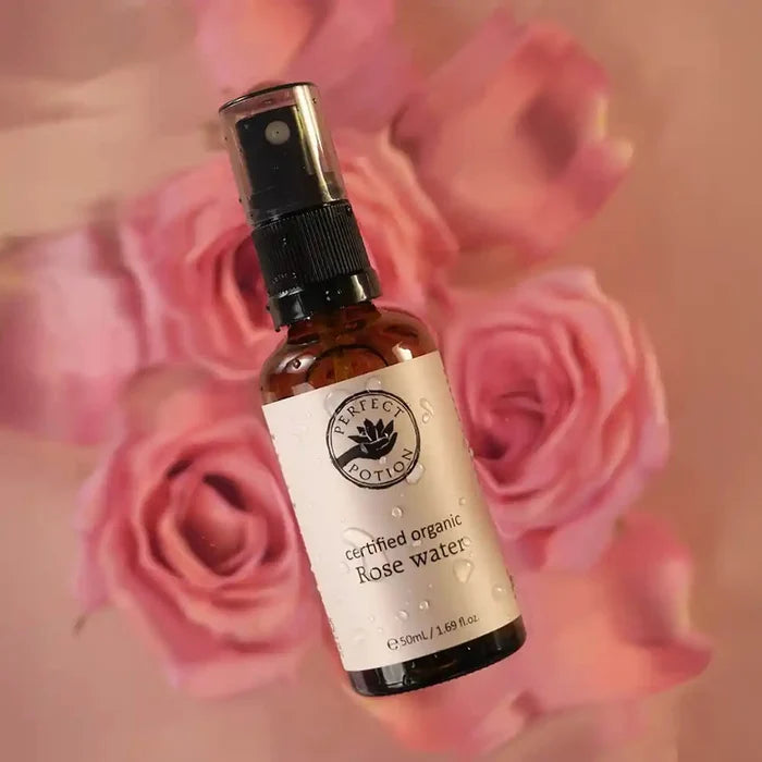 Bottle of certified organic rose water with pink roses in the background