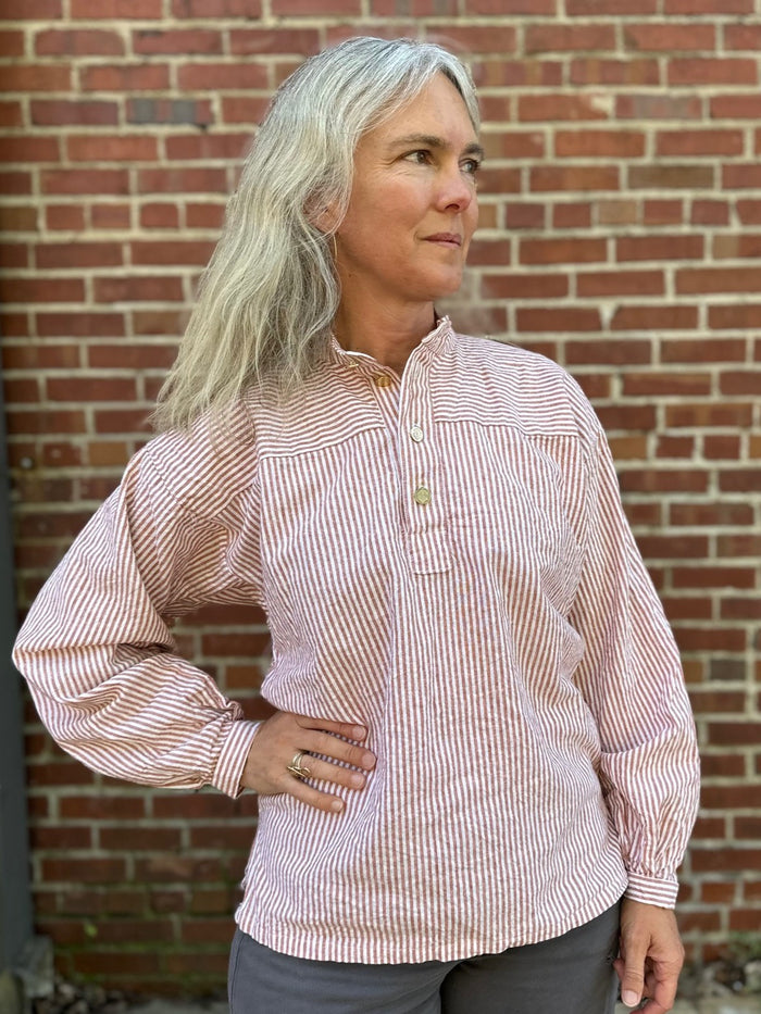 Woman wearing a striped shirt standing against a brick wall