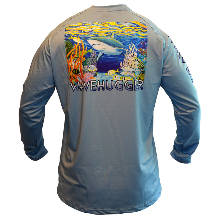 The Blacktip Reef Performance Shirt by Wave Hugger is a light blue long sleeve with a colorful ocean scene—shark, coral, and fish—plus WAVEHUGGER below. Made with UPF 50+ for all-day outdoor comfort.
