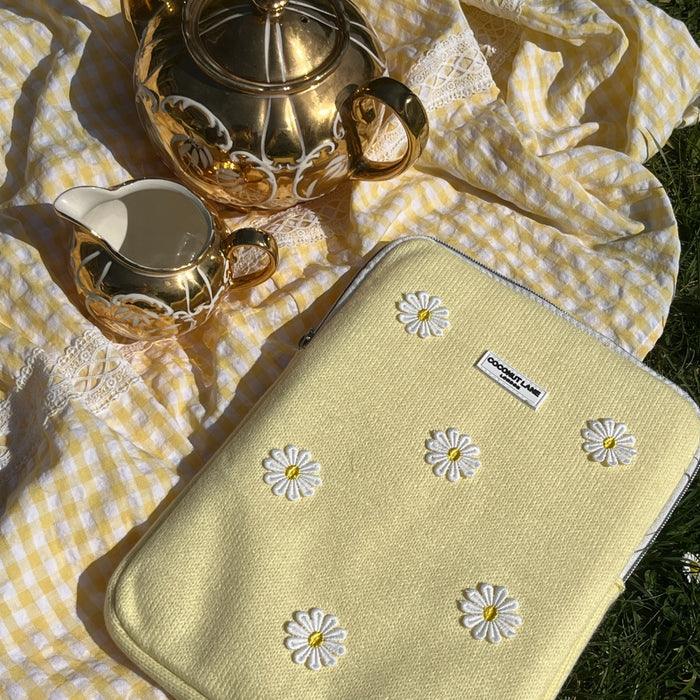 Buttercup Bloom iPad sleeve on yellow gingham with a white daisy pouch and gold teapot beside it.