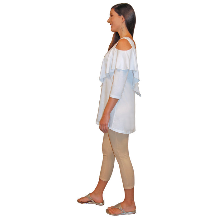 Side view of a woman wearing a white, 3/4 sleeve, flowy top with shoulder cutouts and hem that ends at the top of the thigh, and beige capri pants on a white background.