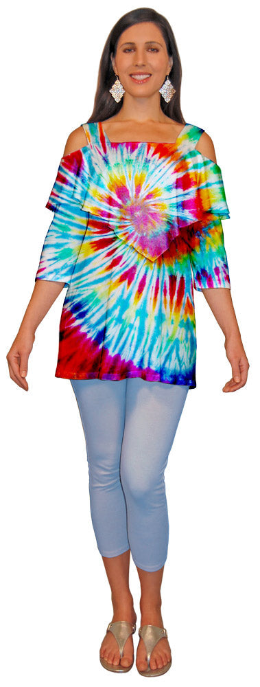 Woman wearing a colorful tie-dyed shoulder cut out top and light blue capri leggings on a white background.