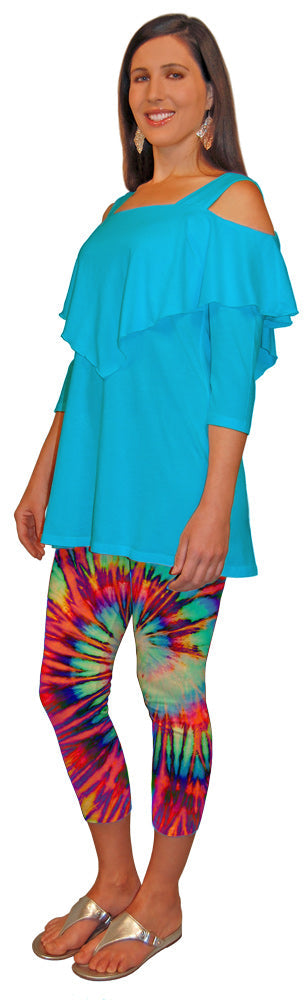 Quarter turn view of a woman wearing a turquoise cold shoulder cut out top and tie-dye leggings on a white background.