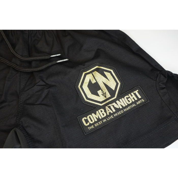 The Retro Grappler Combat Night Gi Shorts are black, lightweight rip-stop shorts with a drawstring and a gold Combat Night logo patch reading The Best in Live Mixed Martial Arts.