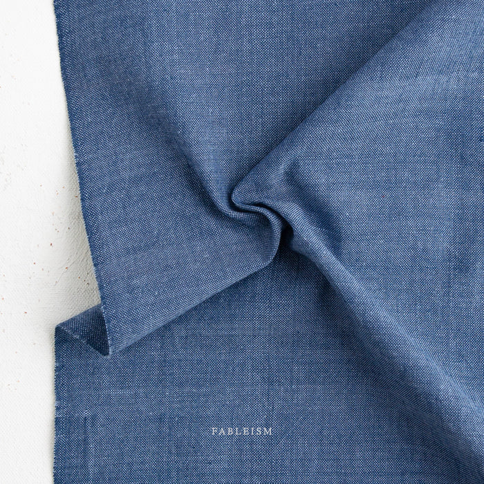 Close-up of blue fabric with 'Fableism' branding on a white background