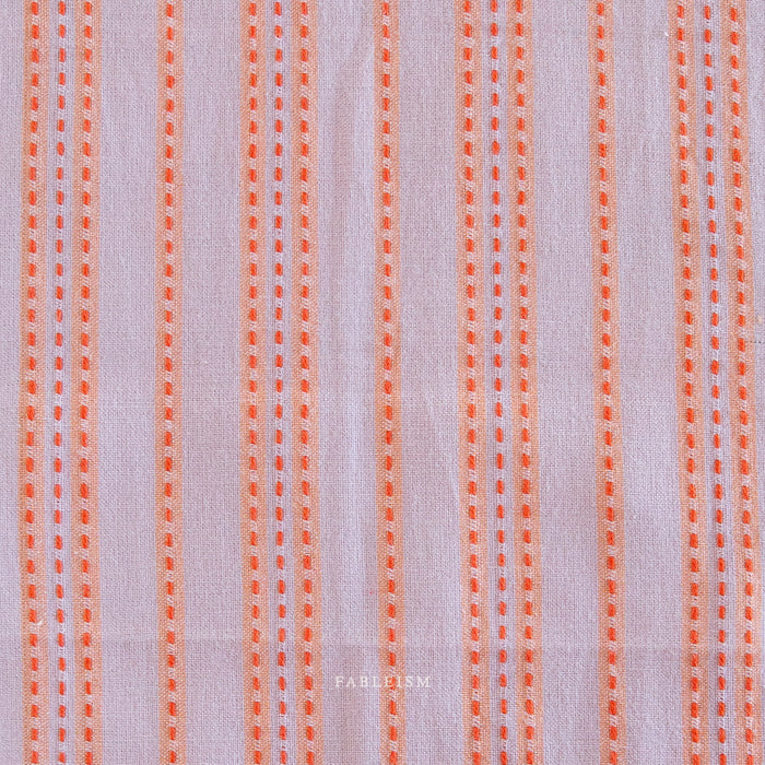 Lavender fabric with orange vertical stitched stripes .