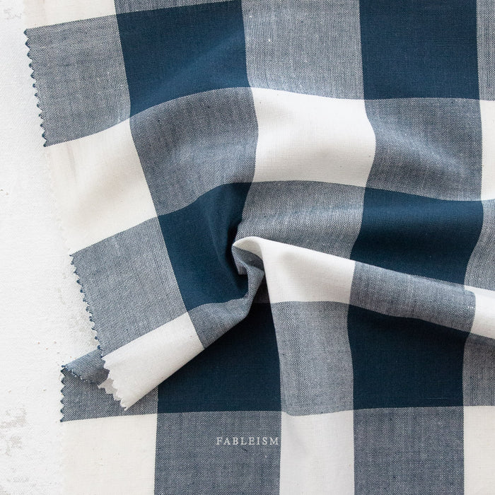 Navy and white checkered gingham fabric on a light background.
