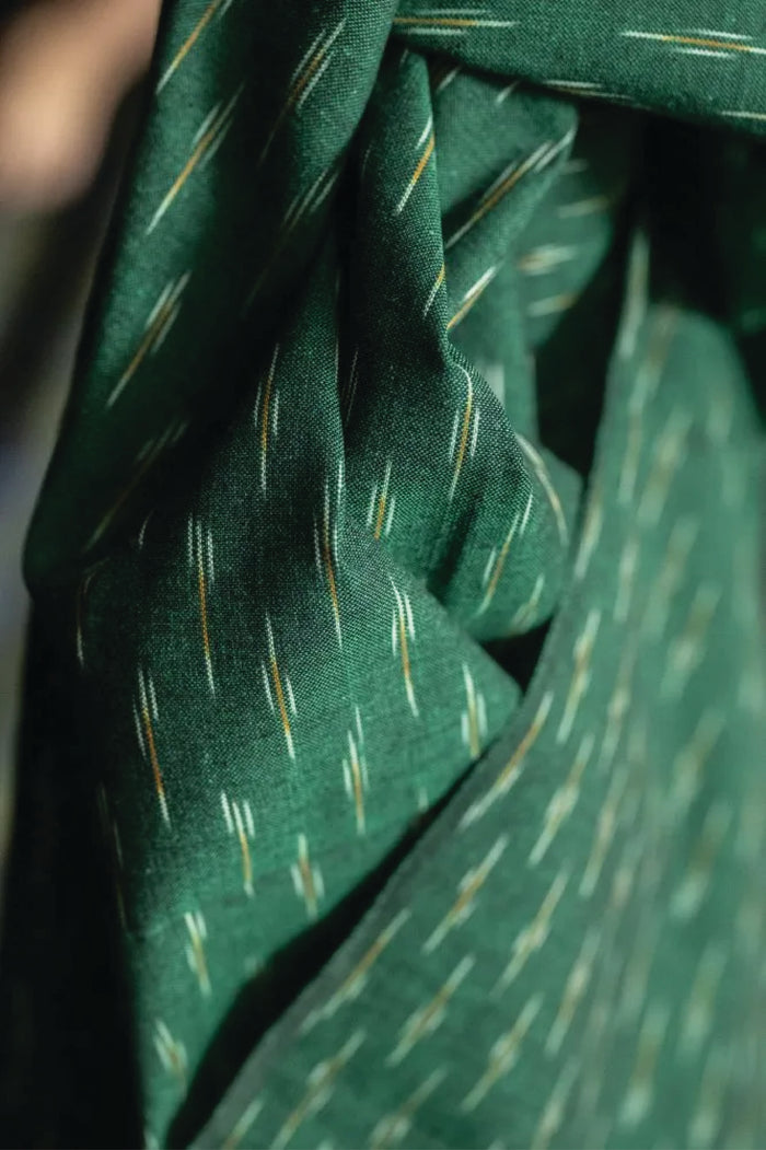 A stunning chequered Ikat weave with ochre and white dashes on a background of dark emerald green.