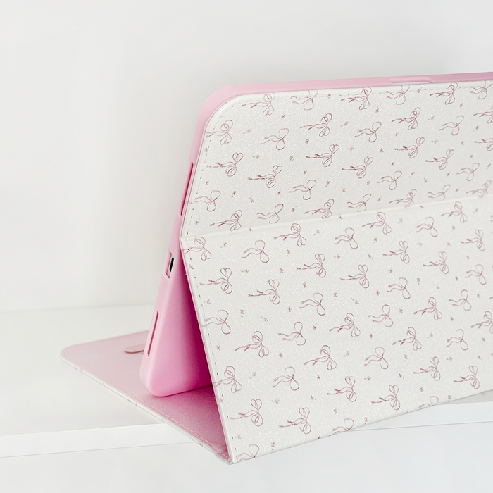 Pink and white iPad case with a white cover decorated with pink bows, designed in a feminine style.
