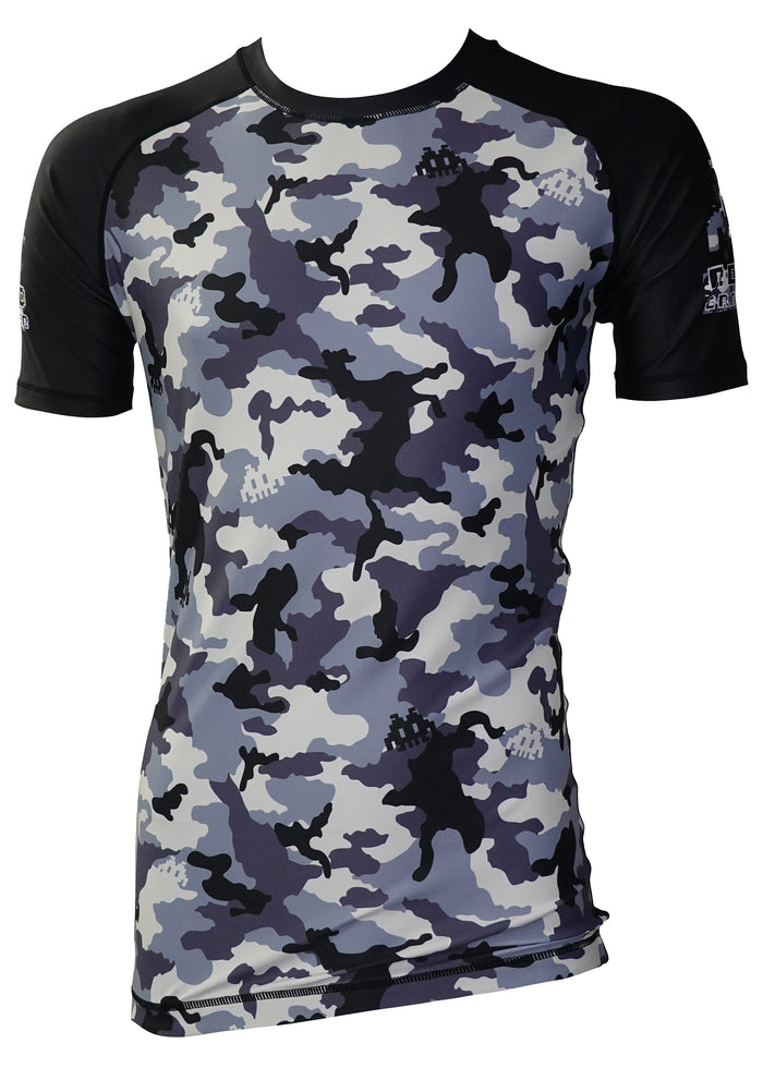 The Dark Woodland Camo Kit by Retro Grappler features a short-sleeve rash guard with black sleeves and a blue, gray, and white camo pattern. Pair it with matching shorts for a complete training set. Displayed on a white background.