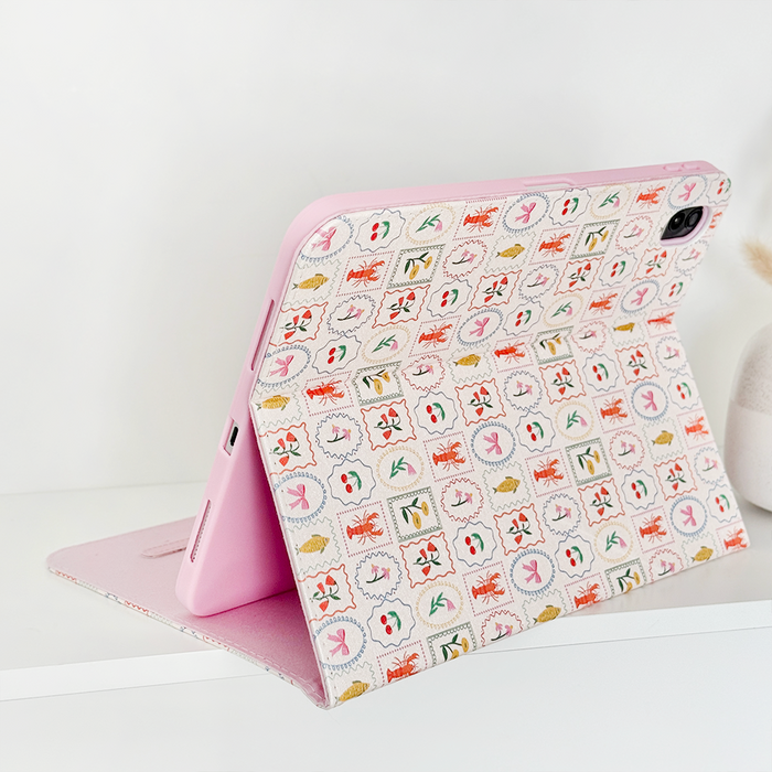 Dolce Vita iPad case by Coconut Lane with colorful stamp pattern, propped open on a white surface.