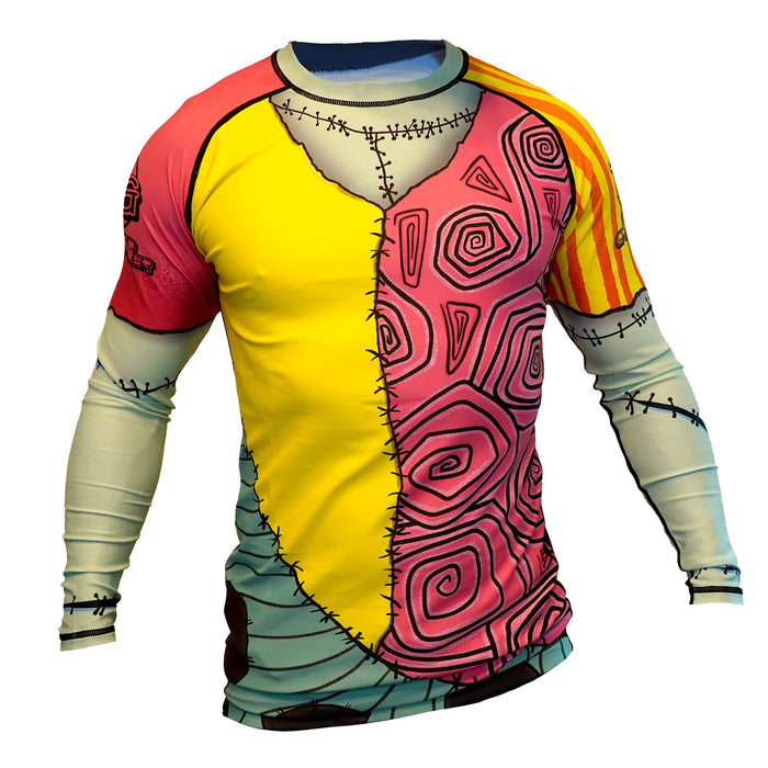 The Retro Grappler Doll Face Nightmare Before Christmas BJJ Rash Guard features long sleeves and a patchwork design with swirled pink, yellow, and bold black stitch details for a whimsical jiu jitsu costume look.