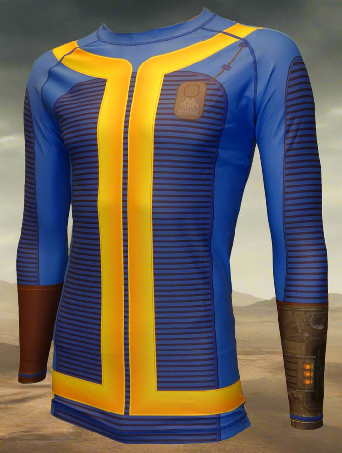 The Retro Grappler Fallout Vault Dweller Rash Guard is a limited edition, long-sleeved blue top with yellow stripes, brown wrist device, and chest patch, inspired by the classic jumpsuit and set against a barren landscape background.