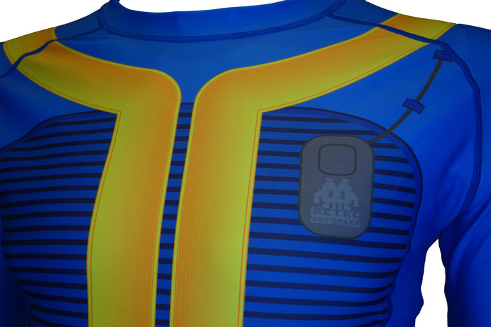 A close-up of the limited edition Fallout Vault Dweller Rash Guard by Retro Grappler, featuring bold blue and yellow stripes, a high collar, and a chest badge with a pixelated alien and RETRO GAMER text.