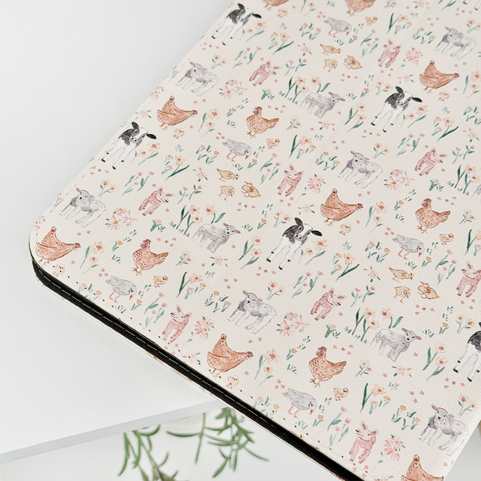 Farmyard Friends iPad case with a playful watercolor pattern of pigs, cows, and flowers on a light background.