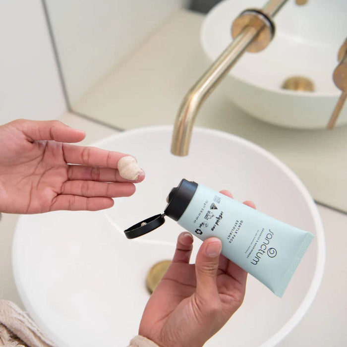 Person applying Gentle Face Exfoliant to their hand over a sink.