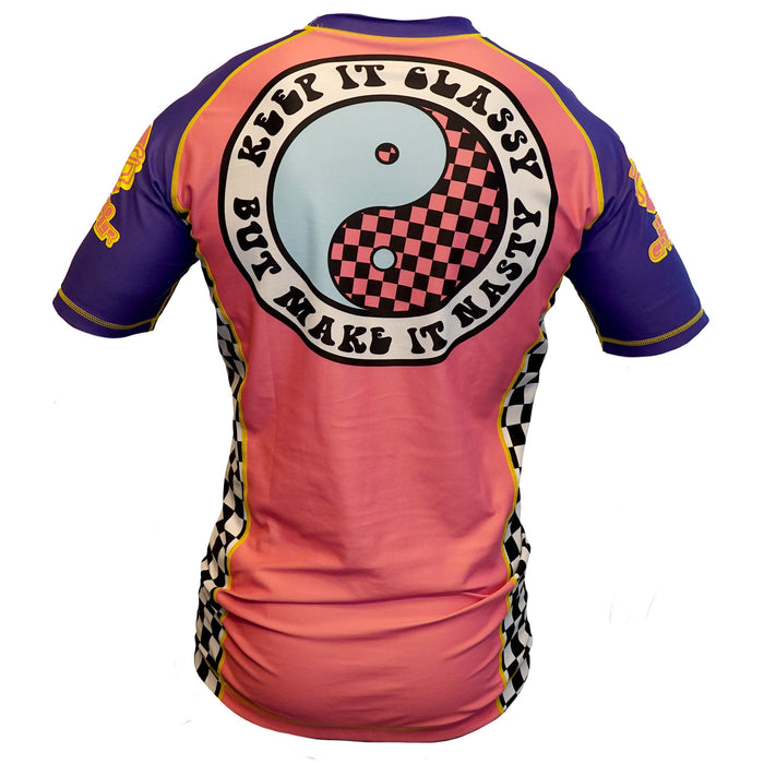 The Retro Grappler Gnarly Surf Rash Guard features short sleeves, a bold checkered yin-yang and Keep it classy but make it nasty on the back, plus pink, purple, and yellow colors with checkered side panels.