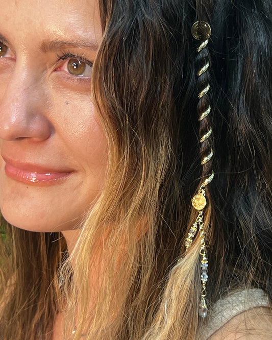 Woman wearing a 4-inch gold Hair Twister spiral hair wrap with crystal charm accent, securing a section of hair as decorative hair jewelry, side view.