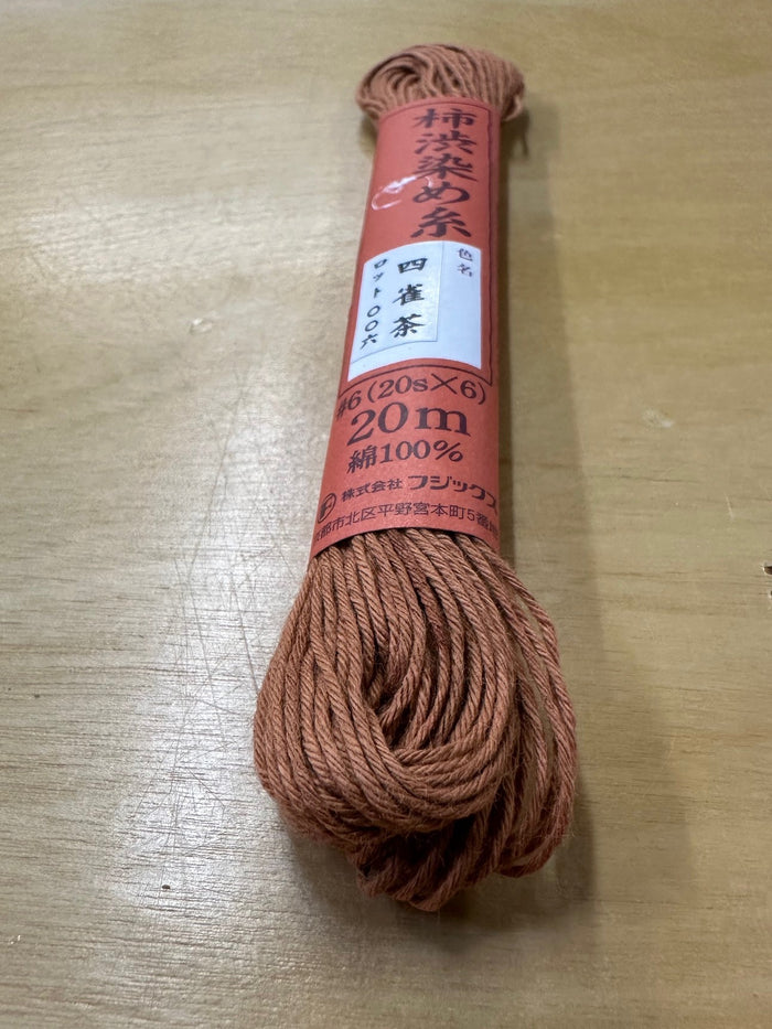 close up photo of red sashiko thread on a tan table