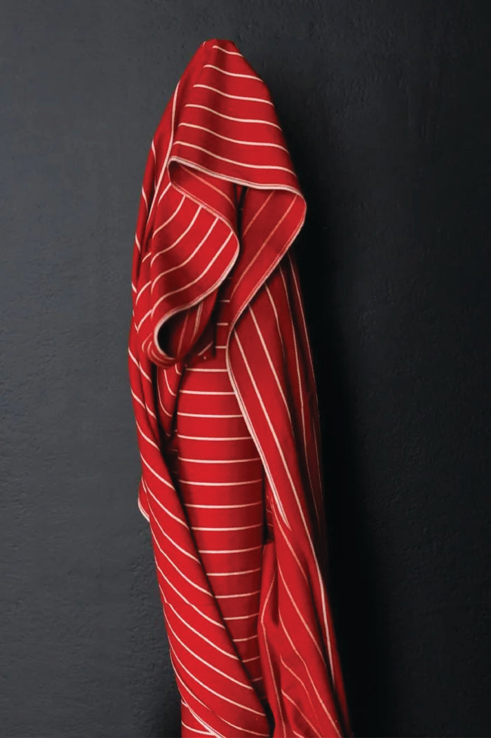 A wide red and think white striped fabric on a dark grey background.