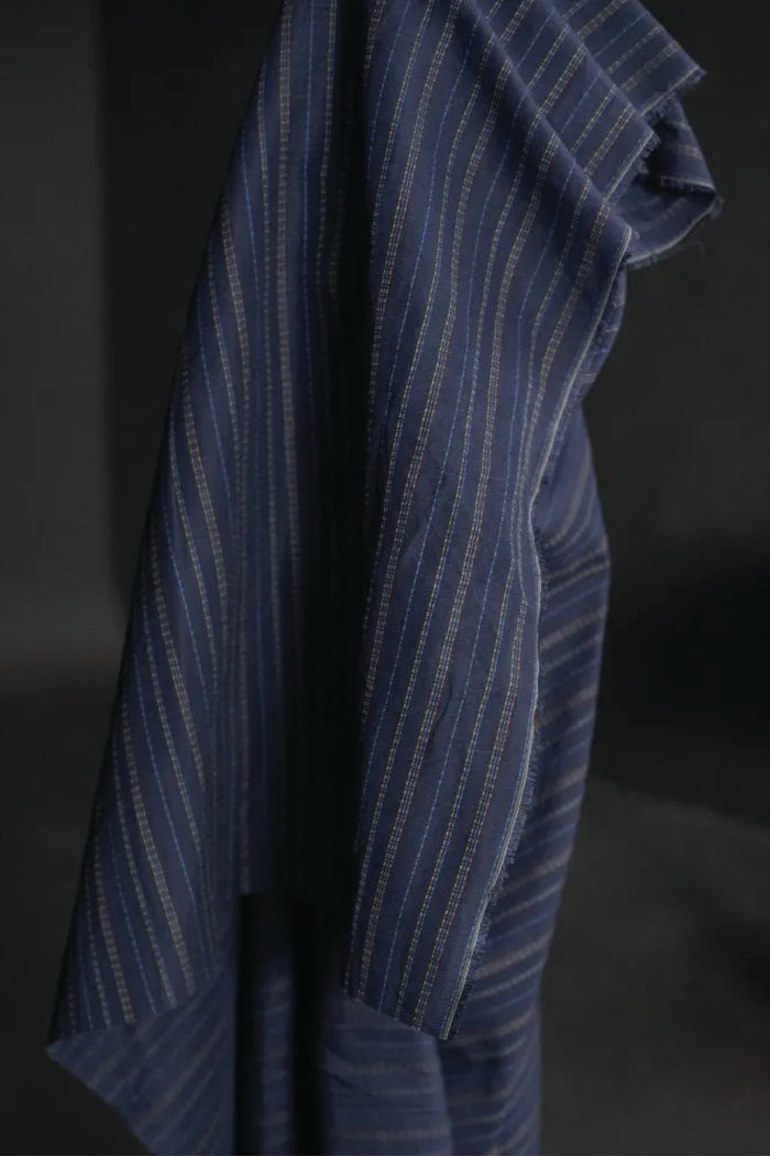 linen/cotton blend in a dark blue fabric with green, blue and tan stitch detail running parallel to the selvedge