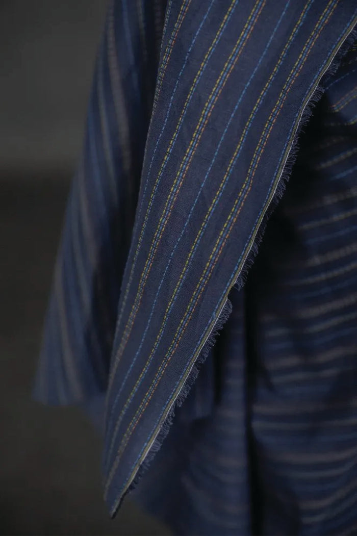 linen/cotton blend in a dark blue fabric with green, blue and tan stitch detail running parallel to the selvedge