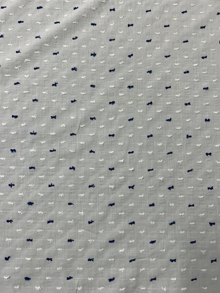 Italian cotton fil coupé fabric features a subtle jacquard-woven Swiss Dot pattern in white and navy on a white background.