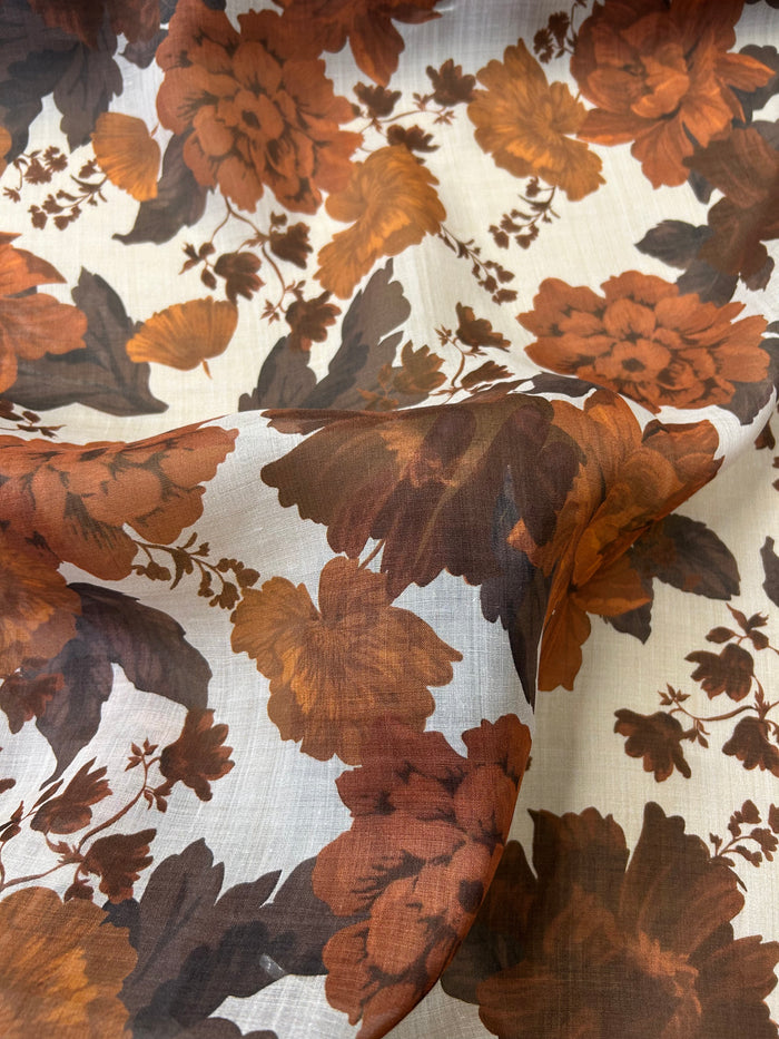Close-up floral peony pattern with brown and orange flowers on a light tan background.