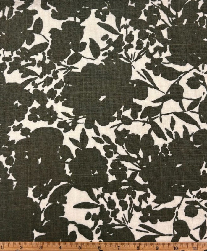 Italian linen with a green print of floral silhouettes on a white background with a ruler at the bottom for scale.