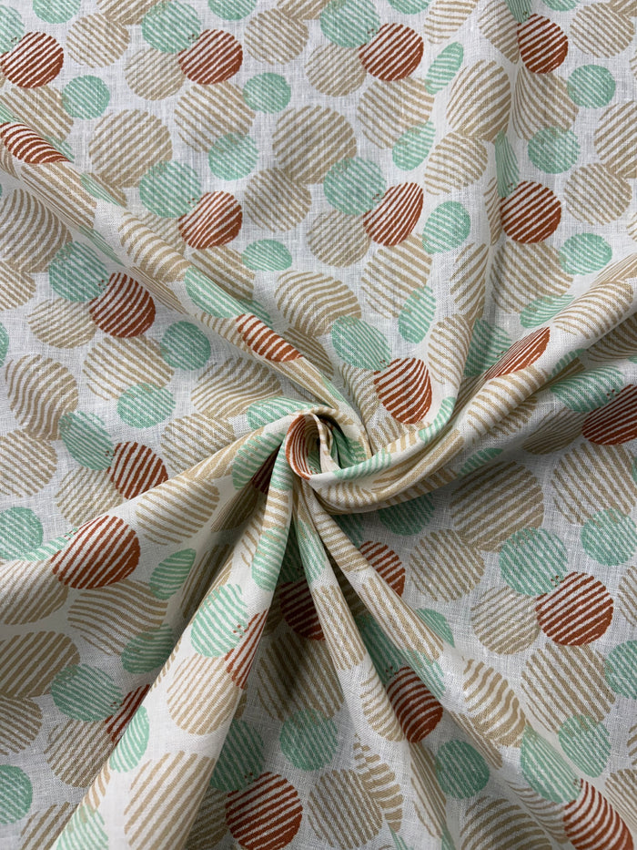 Close-up of patterned Linen fabric with a a retro abstract polka dot print fabric in mint, beige, and rust on an ivory background. The circles vary in size and are filled with fine diagonal stripe textures, creating a layered geometric look with a hand-printed feel.