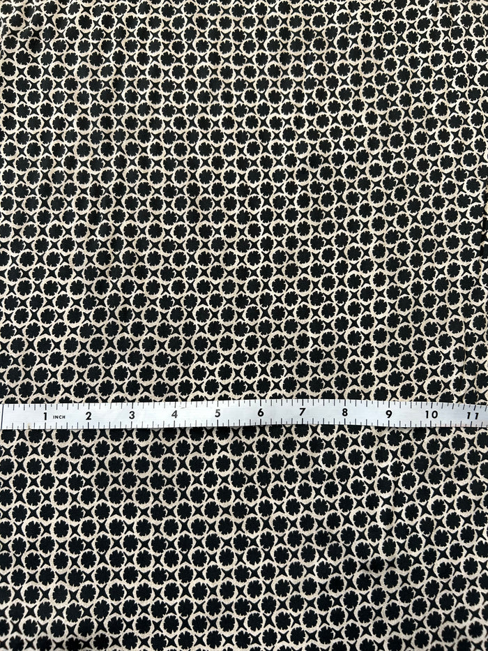 vintage-style, black and tan geometric print, made of viscose with a satin finish with white tape measure on top of fabric.
