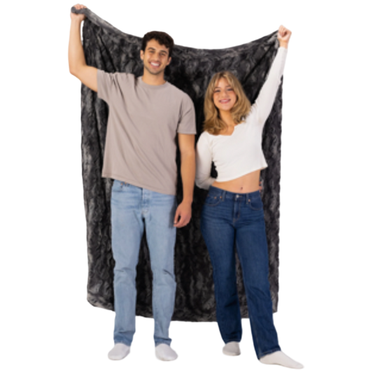Two people holding up a large black and gray patterned blanket against a white background