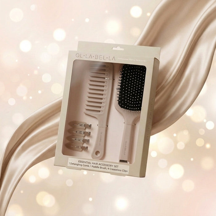 The Olla Bella Knot Today Detangling Brush Kit in its box, containing a detangle brush, a paddle brush, and four creaseless sectioning clips, displayed against a warm, glowing bokeh background.