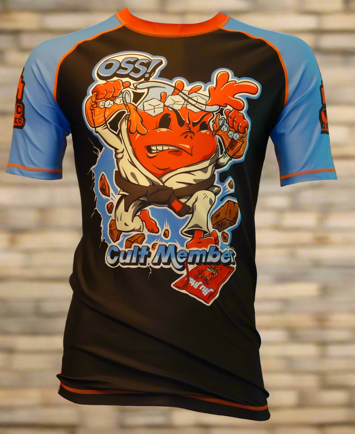 The Retro Grappler Kool-Cult Rashguard Kool Aid Parody is a colorful, limited edition rashguard with four-way stretch, blue sleeves, and an orange cartoon breaking through bricks. OSS! cult Member text—perfect for any jiu-jitsu enthusiast.