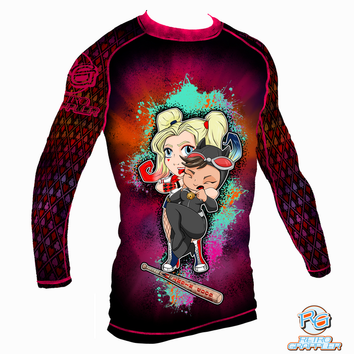 The Lil Jiu Jitsu Monster Rash Guard by Retro Grappler features cartoon Harley Quinn with a bat and Catwoman with a whip on colorful splatter and diamond-patterned, four-way stretch polyester spandex sleeves.