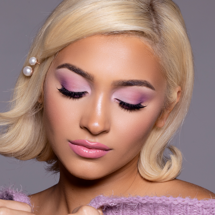 Model wearing Lip to Lip pink lip gloss with purple eyeshadow and blonde hair