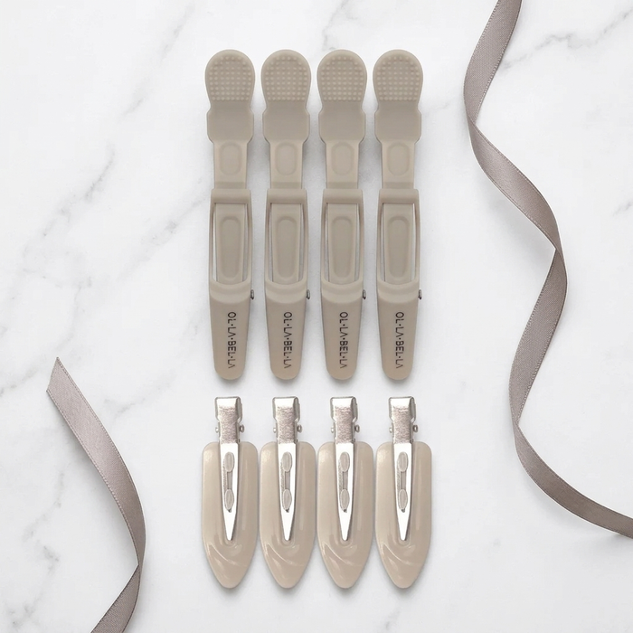 Four Olla Bella Crocodile Clips and four Olla Bella Creaseless Clips from our Olla Bella Mane Master Hair Clip Set arranged in two rows of two on a light marble background with ribbons.