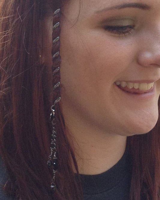 Woman wearing a 4-inch gun black Hair Twister spiral hair wrap with dangling charm accent, securing a section of hair for a boho-inspired hairstyle, side view.
