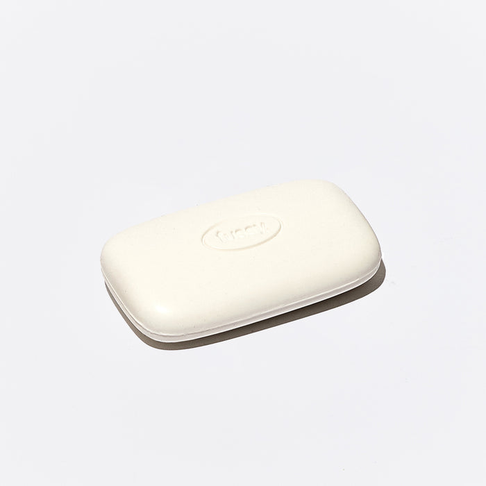 One singular, white bodywash bar from Fussy, set at an angle.