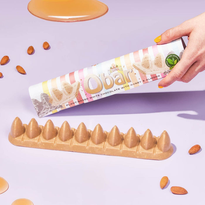 Obar chocolate bar with almond pieces and liquid honey on a light purple background.