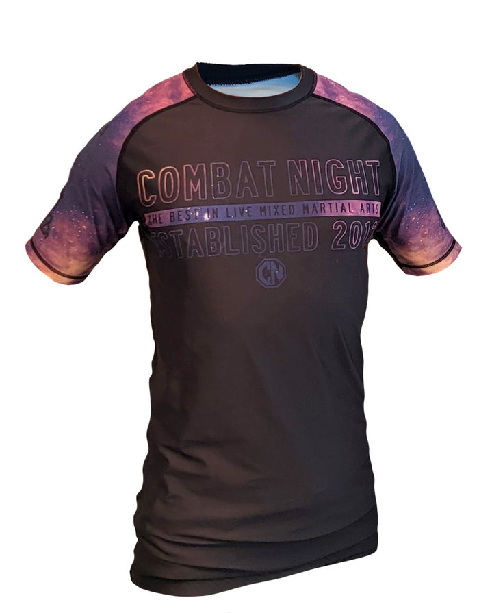 The Retro Grappler Only a Fighter Knows Galaxy Rashguard is a black short-sleeve athletic shirt with purple galaxy-patterned sleeves, fitted design, four-way stretch, and Combat Night: The Best in Live Mixed Martial Arts, Established 2012 on the front.