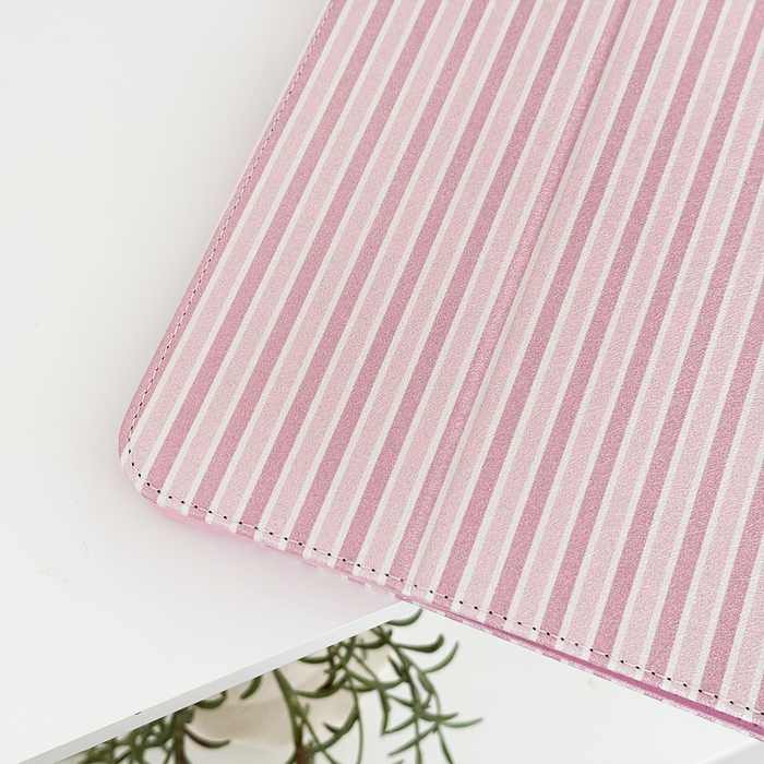Powder Stripes iPad case by Coconut Lane with a striped design on a table, plant leaves visible in the corner.