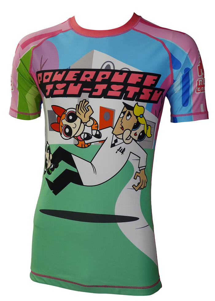 The Retro Grappler Power Puff Jiu Jitsu Rash Guard is a colorful, short-sleeve rashie with four-way stretch, featuring Blossom, Bubbles, Buttercup, Professor Utonium, and the words “Powerpuff Jiu-Jitsu.”.
